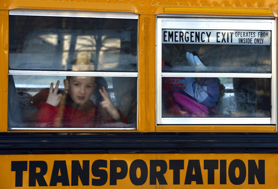 A Sandy Hook Elementry student flashes a sign as children leave on a school bus  in Newtown , Connecticut January 3, 2013.  Students at the elementary school where a gunman massacred 26 children and teachers last month were returning Thursday to classes at an alternative campus described by police as "the safest school in America." .