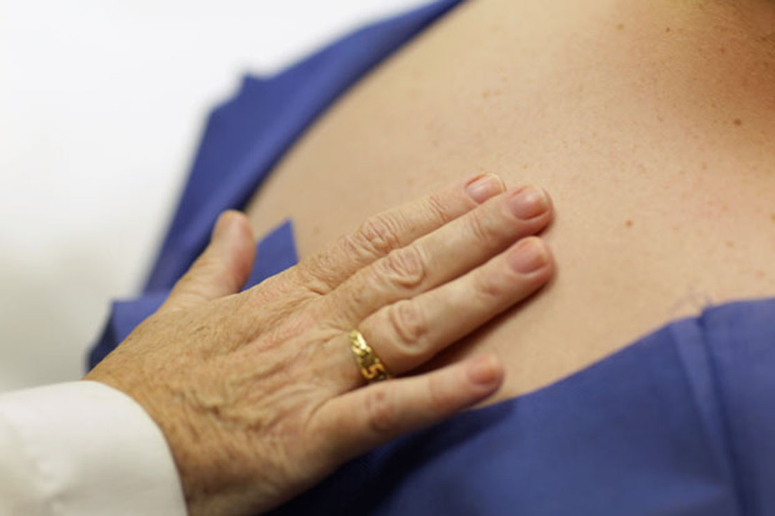 A doctor places his hand on his patient's back during a routine check up.