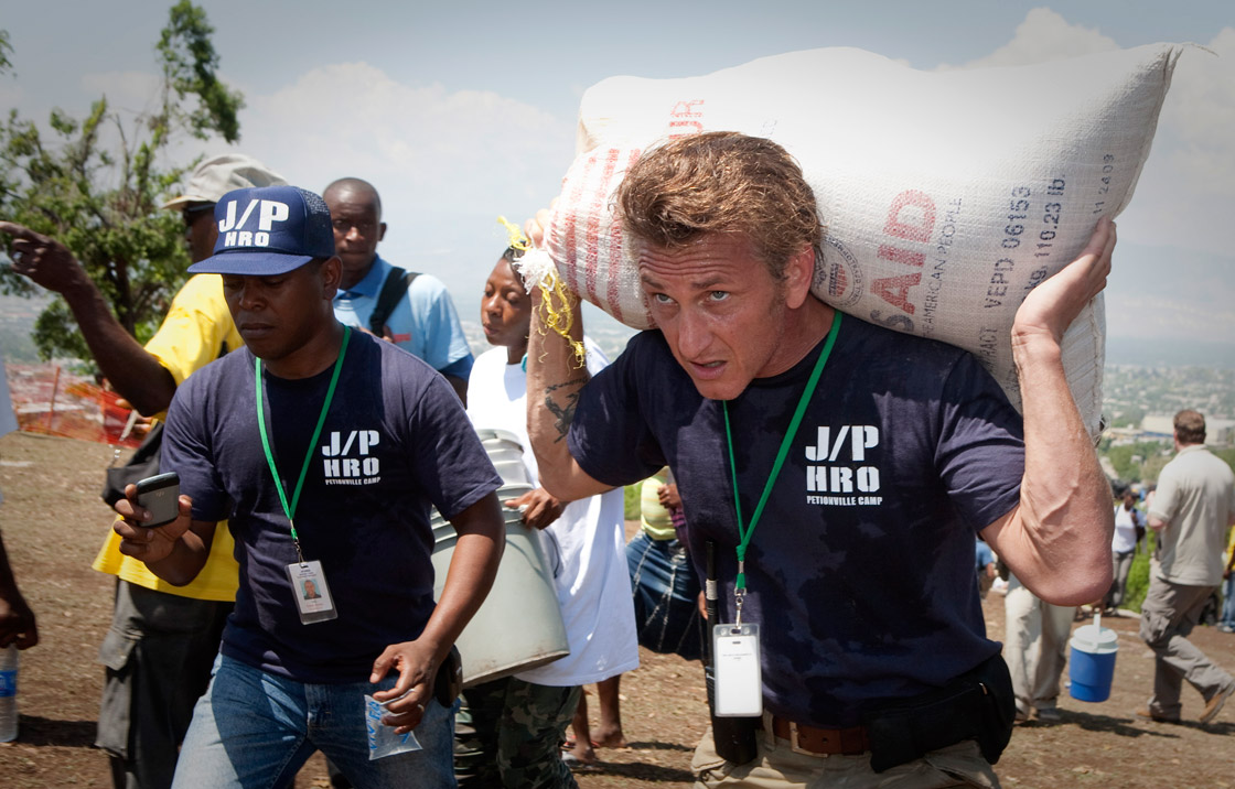 Actor Sean Penn carries belongings of a shelter camp resident as they are prepared to be relocated to a new camp April 10, 2010 in Petionville, Haiti. 