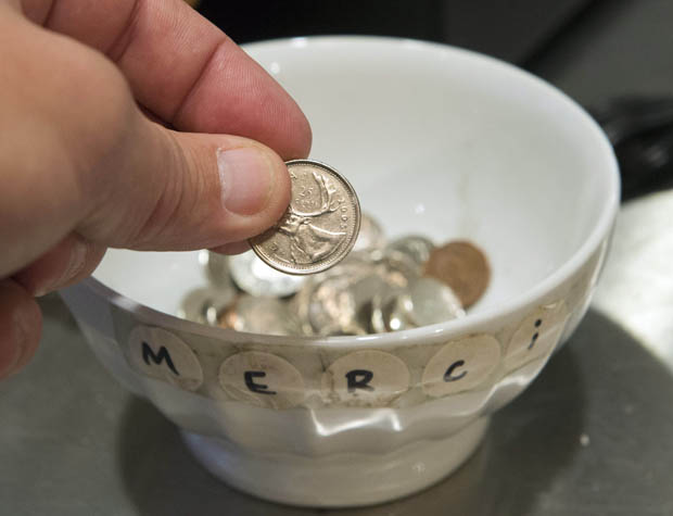A customer drops a coin in a tip jar.
