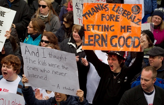 Seventeen-year-old Ian Walston;right;a grade 12 student at New Westminster Secondary School;holds a sign and cheers during a rally in support of striking teachers in Vancouver;B.C.;on Wednesday March 7;2012. B.C. teachers were joined by students and other supporters on the final day of a three-day walkout.