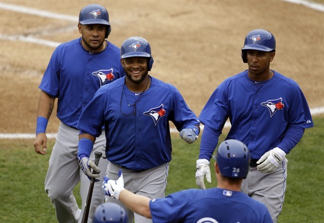 Toronto Blue Jays' Melky Cabrera, from left, Emilio Bonifacio and Anthony Gose are congratulated by Adam Lind after teammate J.P. Arencibia doubled to left-center field, allowing the three to score, during the first inning of an exhibition spring training baseball game against the Baltimore Orioles, Wednesday, March 20, 2013 in Sarasota, Fla.