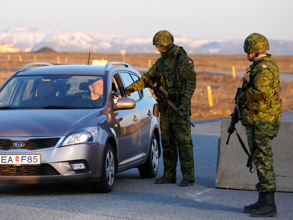 Cpl Gary Glasius stops a vehicle for an identification check at a Canadian checkpoint at the Keflavyk Base in Iceland during Operation Ignition 2013.