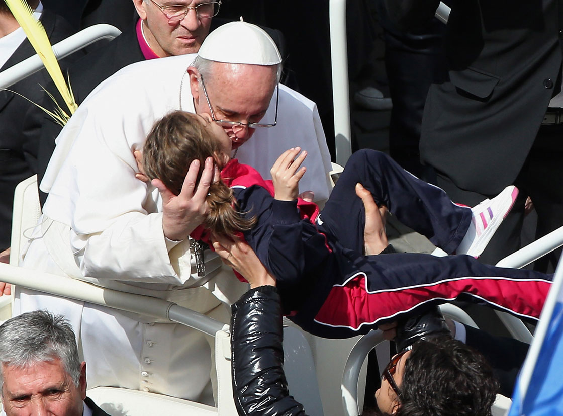 VATICAN CITY, VATICAN - MARCH 24: Pope Francis kisses a child as he greets the faithful after conducting Palm Sunday Mass on March 24, 2013 in Vatican City, Vatican. Pope Francis lead his first mass of Holy Week as pontiff by celebrating Palm Sunday in front of thousands of faithful and clergy. The pope's first holy week will also incorporate him washing the feet of prisoners in a youth detention centre in Rome next Thursday, 28th March.