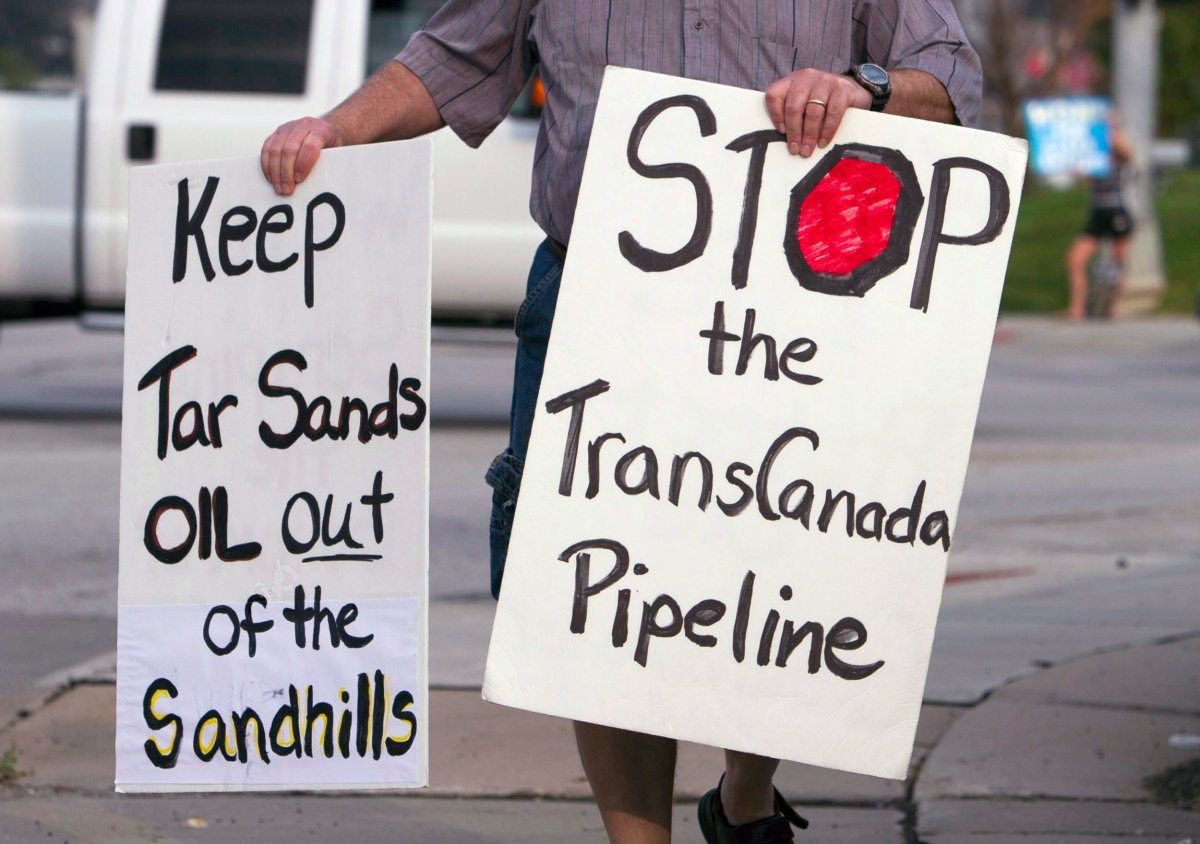In this Sept. 21, 2010 photo, an unidentified protester who is opposed to the Keystone XL pipeline because of environmental reasons, carries signs in Omaha, Neb. A former inspector for a company that did work on TransCanada's original Keystone pipeline is accusing the Calgary-based company of a cavalier disregard for the environment, alleging it cut corners as it laid down the pipe. THE CANADIAN PRESS/AP, Nati Harnik