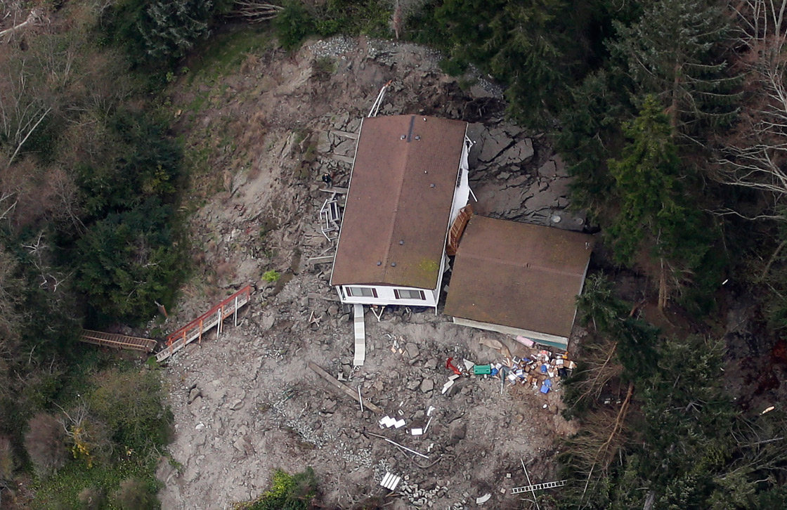 In this aerial photo, a house sits near the bottom edge of a landslide near Coupeville, Wash. on Whidbey Island, Wednesday, March 27, 2013. The slide severely damaged one home and isolated or threatened more than 30 on the island, about 50 miles north of Seattle in Puget Sound. No one was reported injured in the slide, which happened at about 4 a.m. Wednesday. 