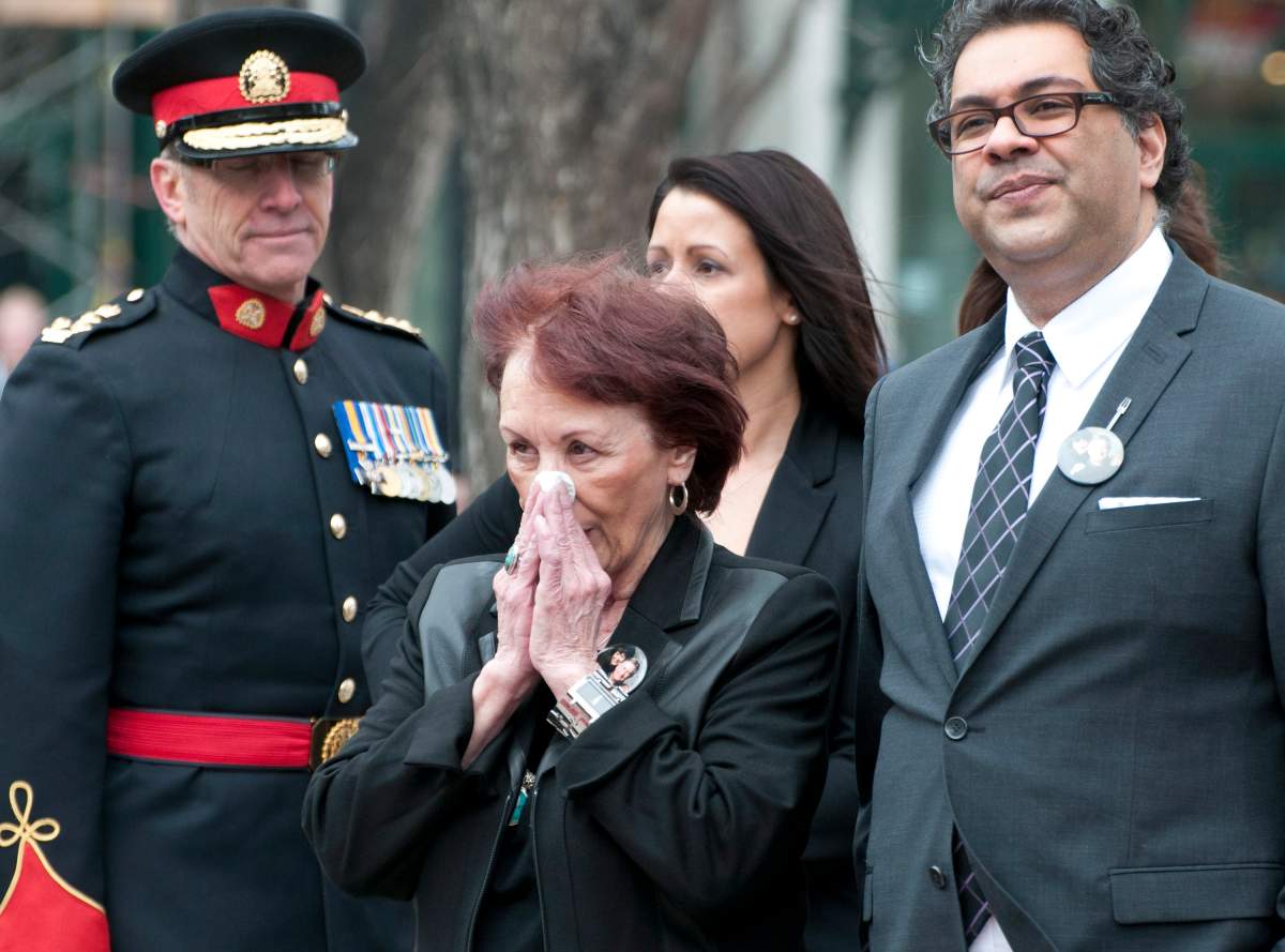 Widow Colleen Klein, centre, gets emotional during a public memorial service for former premier, and Calgary mayor, Ralph Klein at City Hall in Calgary on Friday, April 5, 2013. At right is Calgary Mayor Naheed Nenshi and left is Calgary police chief Rick Hanson. THE CANADIAN PRESS/Larry MacDougal