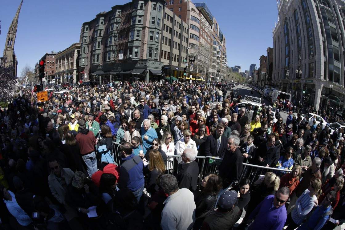 In this photograph made with a fisheye lens, people attend an interfaith service held near a makeshift memorial on Boylston Street, near the finish line of the Boston Marathon, Sunday, April 21, 2013, in Boston. The city is coping in the aftermath of the marathon bombing. (Julio Cortez / AP Photo)