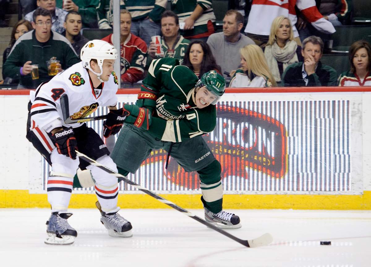 Zach Parise #11 of the Minnesota Wild and Niklas Hjalmarsson #4 of the Chicago Blackhawks go after the puck during the game on April 9, 2013 at Xcel Energy Center in St Paul, Minnesota. (Photo by Hannah Foslien/Getty Images).
