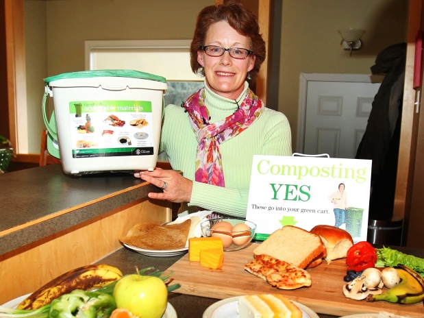 Green cart program manager Paula Magdich does a home demonstration of collecting and disposing of food and yard waste for the green cart pilot program.