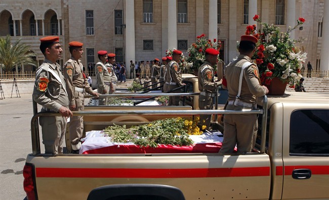 Security forces escort the coffins of five slain soldiers at the headquarters of the Iraqi Ministry of Defense in Baghdad, Iraq, Sunday, April 28, 2012. Gunmen killed 10 people in Iraq, including five soldiers near the main Sunni protest camp west of Baghdad on Saturday, the latest in a wave of violence that has raised fears the country faces a new round of sectarian bloodshed.