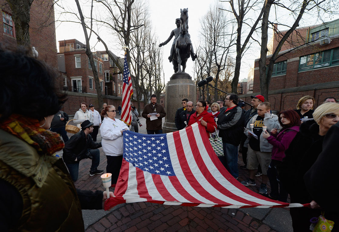 People hold an American flag during a candlelight vigil for victims of  Boston Marathon bombings on April 21, 2013 in Boston, Massachusetts. 