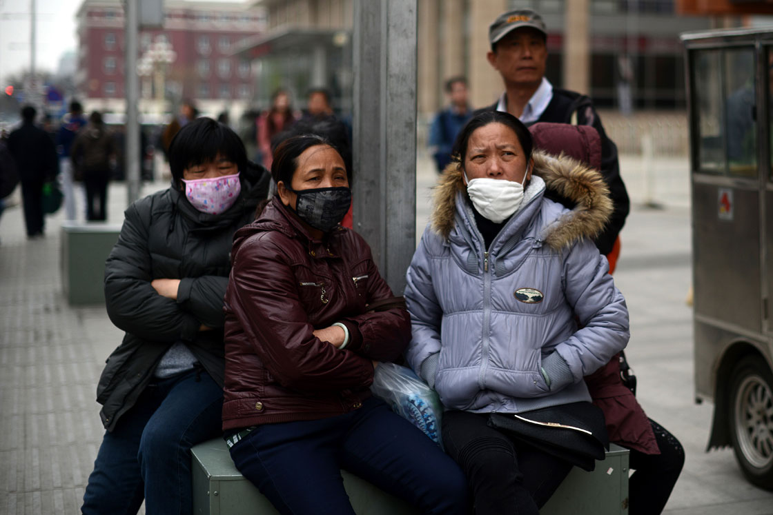 A group of Chinese women wear face masks as they sit on a street side in Beijing on April 19, 2013. 