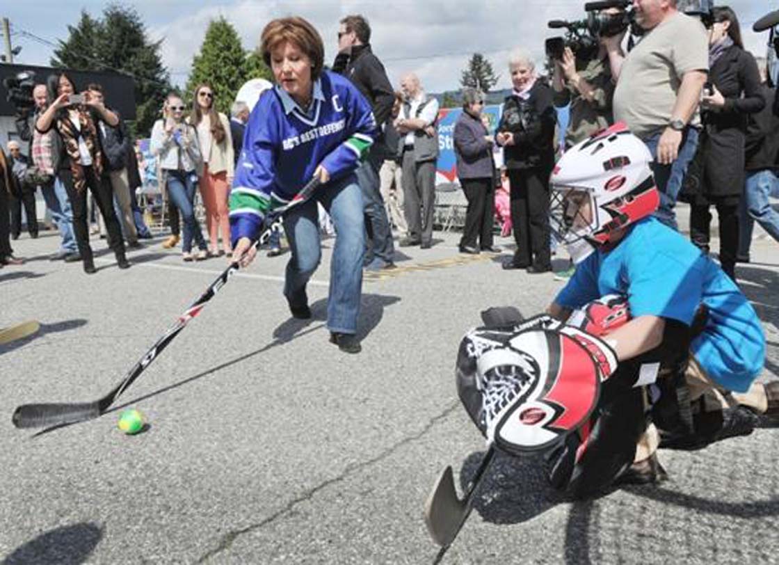 Christy Clark wears a faux Canucks jersey as she plays ball hockey against goalie Brian Heilman, 6, during a campaign stop Sunday in North Vancouver.