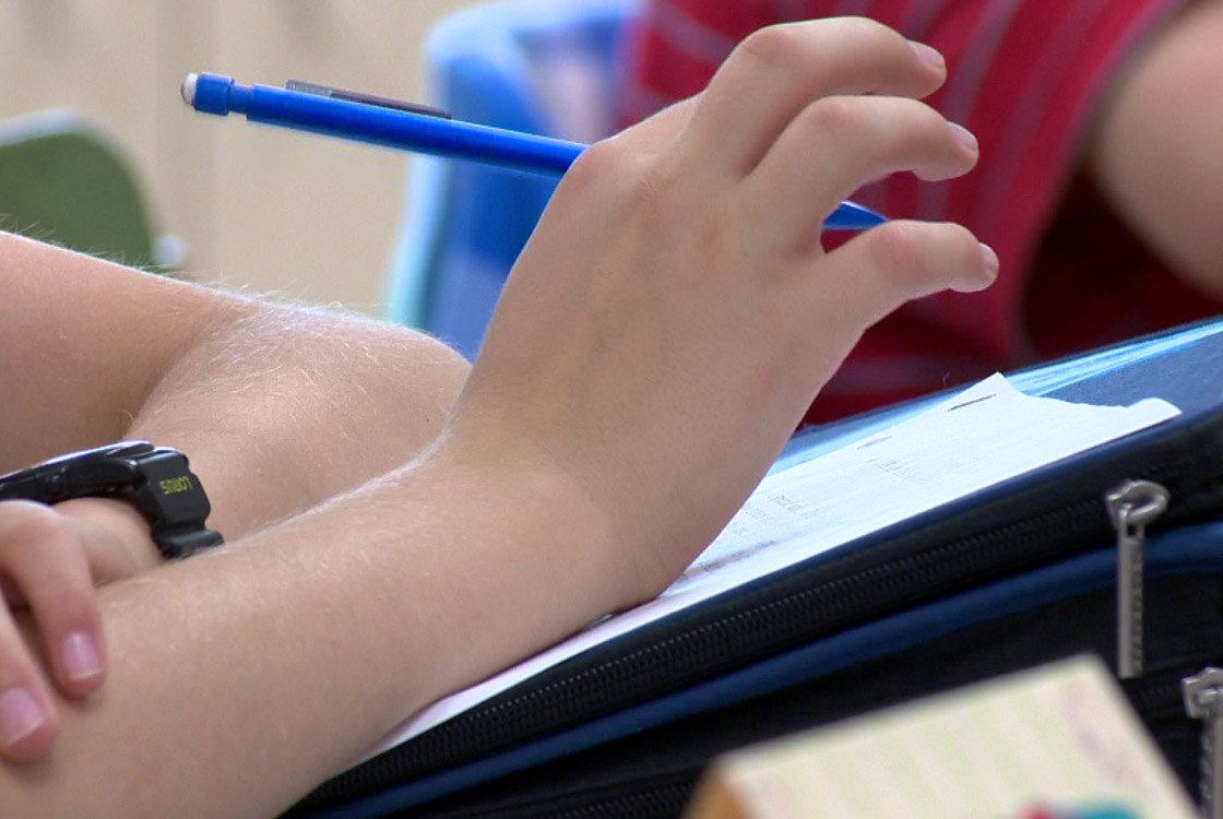 Close-up of child's hand with pen at a desk.