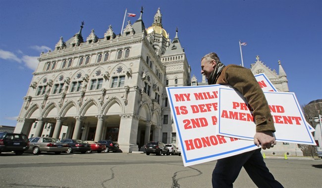 Jody Winslow, of Farmington, Conn., carries signs regarding the second amendment of the U.S. Constitution near the statehouse in Hartford, Conn. ahead of a vote in the General Assembly on proposed gun-control legislation. 