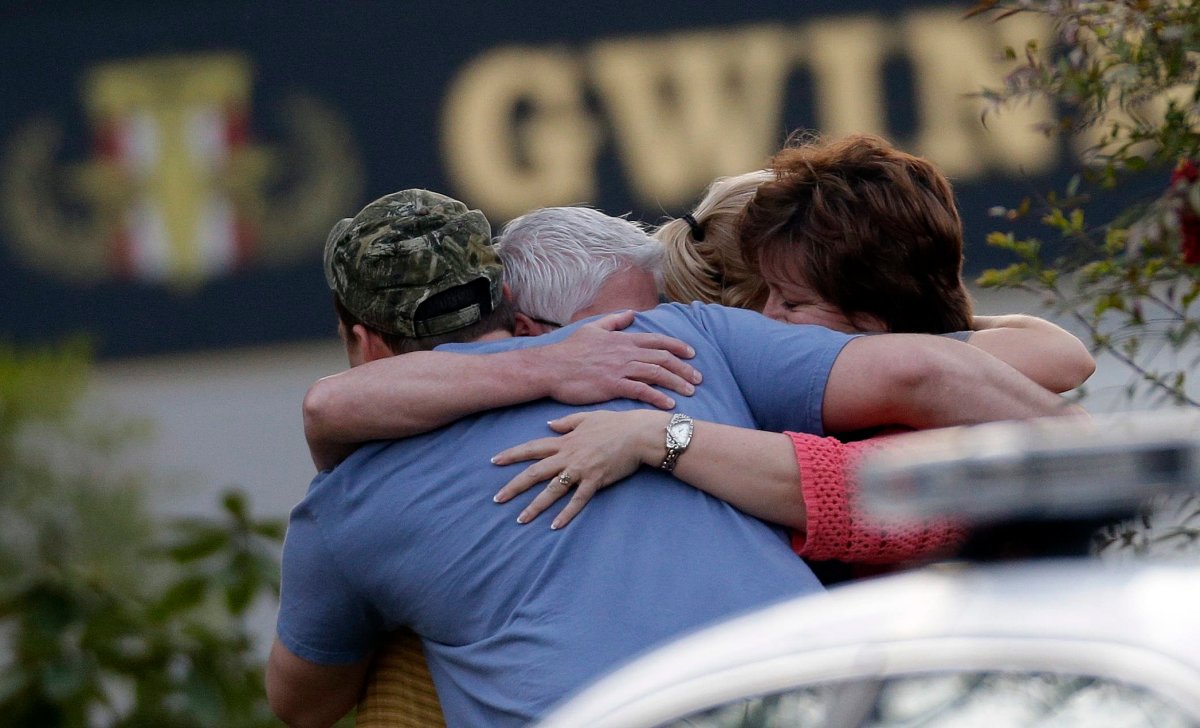A group of people huddle together after an explosion and gunshots were heard near the scene where a man was holding four firefighters hostage Wednesday, April 10, 2013 in Suwanee, Ga. A police spokesman said the suspect was dead and none of the hostages suffered serious injuries.  (AP Photo/John Bazemore).