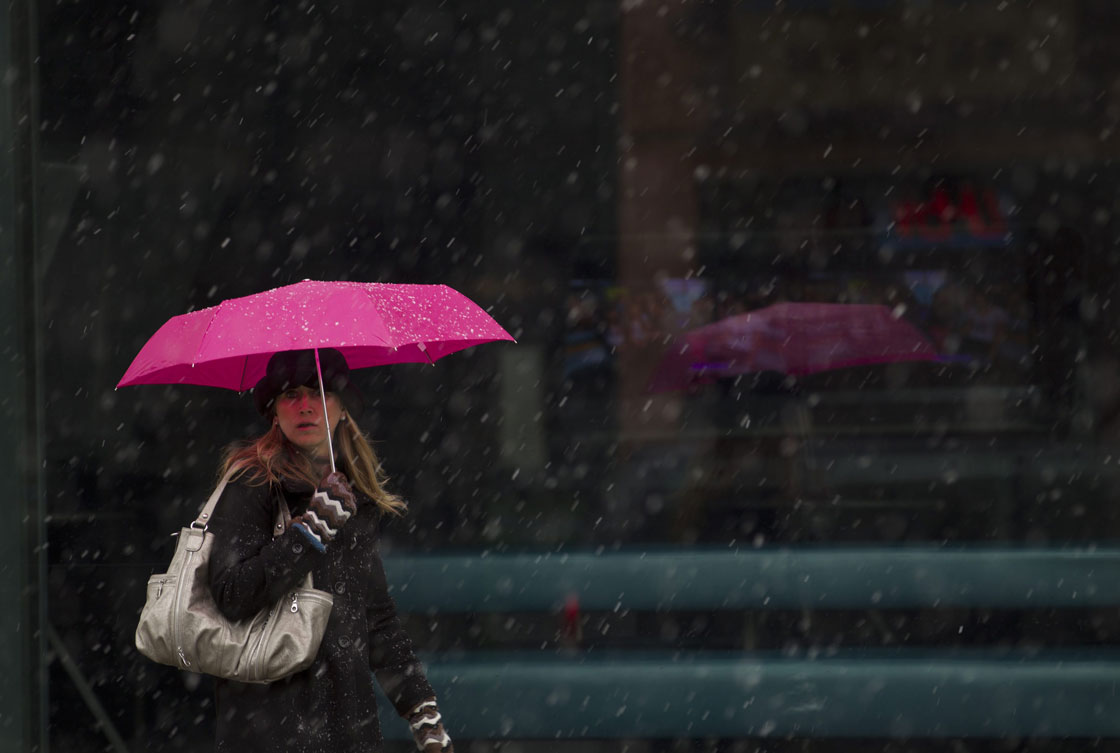 A woman walks along Queen Street while wet snow and rain falls in Toronto on Jan. 27, 2012. 