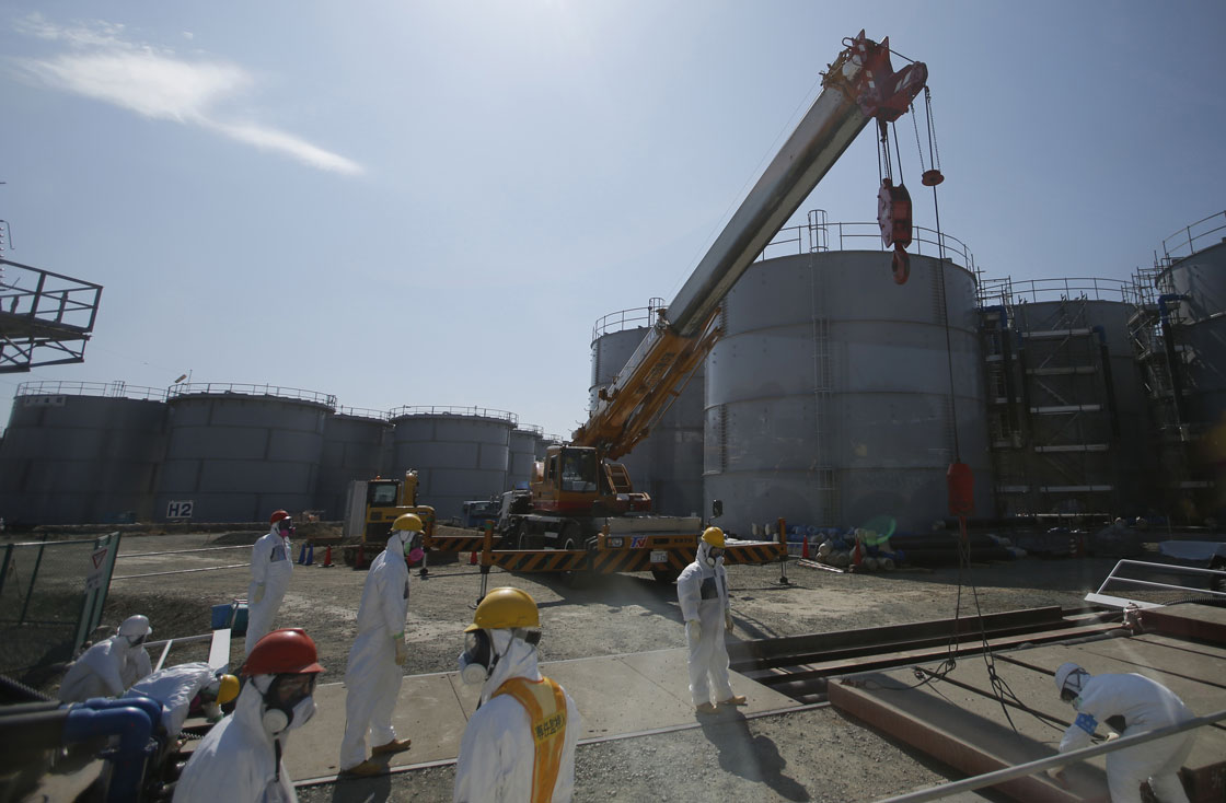 Workers wearing protective suits and masks are seen near tanks of radiation contaminated water at Tokyo Electric Power Co's (TEPCO) tsunami-crippled Fukushima Daiichi nuclear power plant in the town of Okuma, Fukushima prefecture on March 6, 2013.