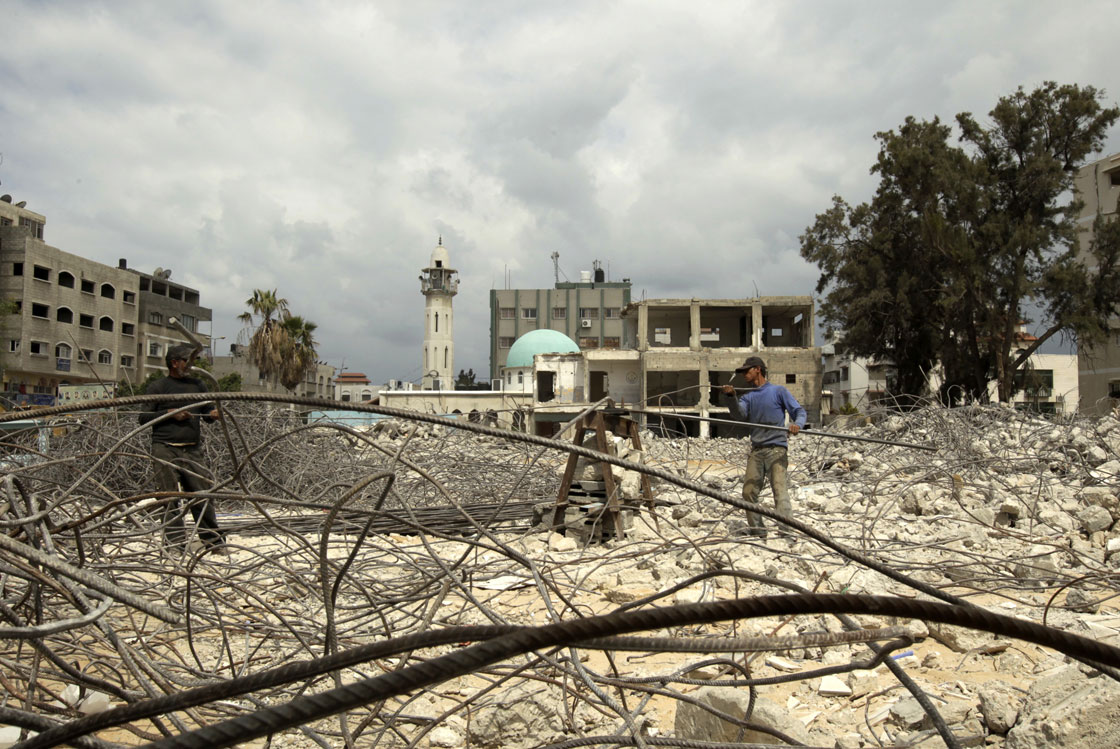 Palestinian workers remove rubble from the ruins of a Hamas security forces headquarters that was destroyed during Israel's last November Gaza campaign, on April 16, 2013. 