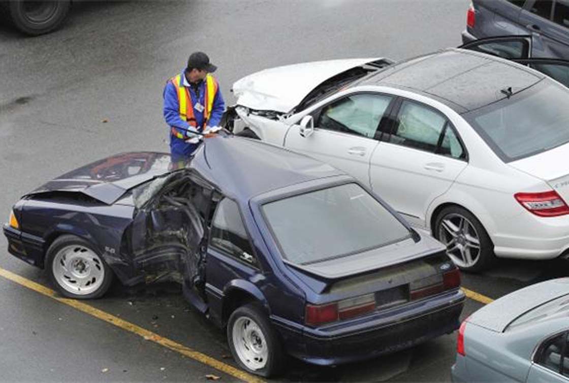 ICBC worker examines wrecked car.