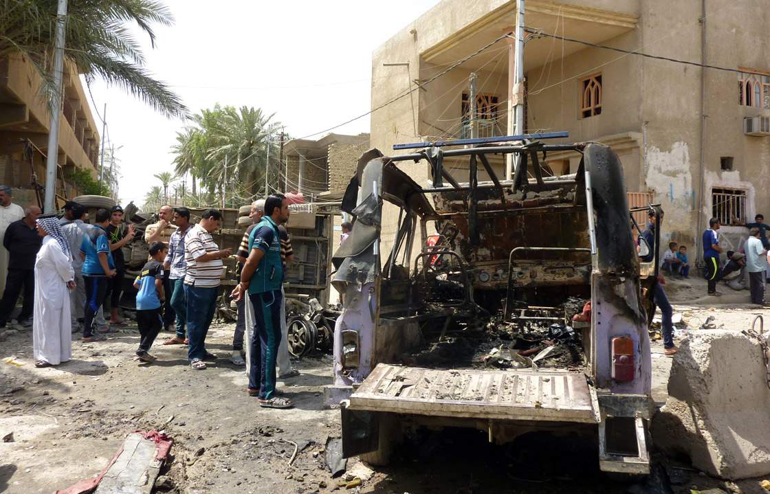 People look at the remains of vehicles damaged following an explosion in the al-Obaidi neighborhood, east of Baghdad on April 15, 2013.
