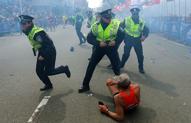 Police officers react to a second explosion at the finish line of the Boston Marathon in Boston, Monday, April 15, 2013. Two explosions shattered the euphoria of the Boston Marathon finish line on Monday, sending authorities out on the course to carry off the injured while the stragglers were rerouted away from the smoking site of the blasts. (AP Photo/The Boston Globe, John Tlumacki)