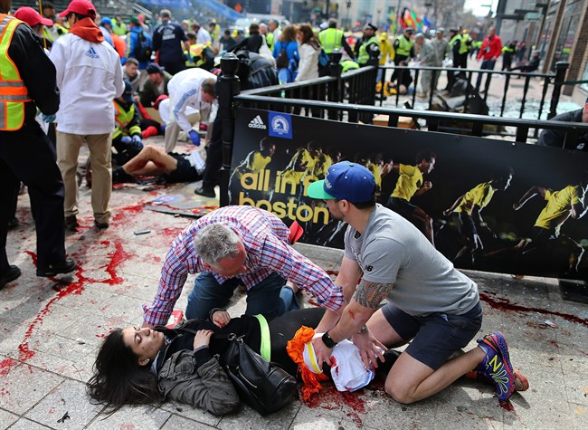 FILE - In this April 15, 2013 file photo, an injured woman is tended to at the finish line of the Boston Marathon after two bombs exploded within seconds of each other. More than 180 people were hurt in the explosions, and at least 14 of them lost all or part of a limb. (AP Photo/The Boston Globe, John Tlumacki, File).
