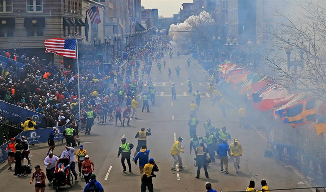 People react as an explosion goes off near the finish line of the 2013 Boston Marathon in Boston, Monday, April 15, 2013.