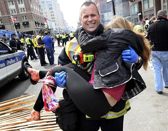 In this Monday, April 15, 2013 file photo, Boston Firefighter James Plourde carries an injured girl away from the scene after a bombing near the finish line of the Boston Marathon.