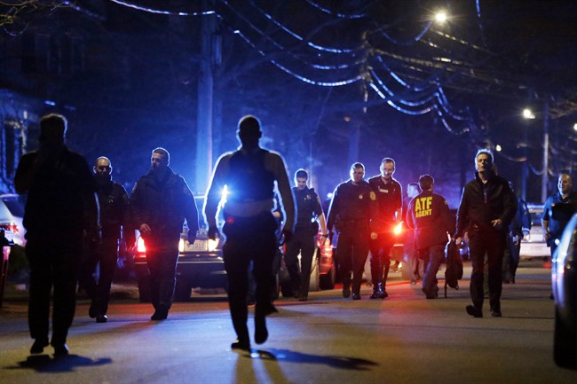 Police officers walk near a crime scene Friday, April 19, 2013, in Watertown, Mass. A tense night of police activity that left a university officer dead on campus just days after the Boston Marathon bombings and amid a hunt for two suspects caused officers to converge on a neighborhood outside Boston, where residents heard gunfire and explosions.
