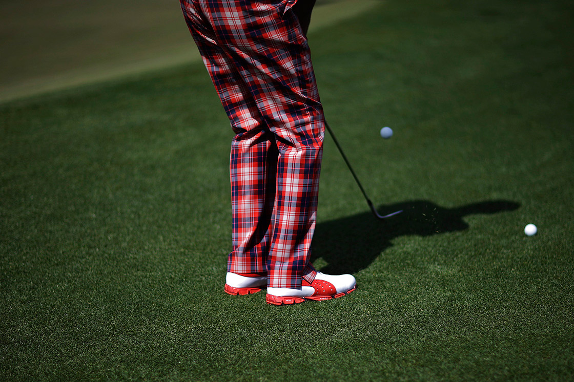 Ian Poulter, of England, wearing checkered pants, chips to the ninth green during a practice round for the Masters golf tournament Tuesday, April 9, 2013, in Augusta, Ga.