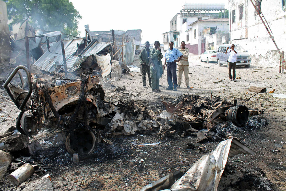 Somali soldiers look at the wreckage of the car that detonated the bomb near the entrance of Mogadishu’s court complex, Mogadishu, Somalia, Sunday, April,14, 2013. Militants launched a serious and sustained assault on Mogadishu's main court complex Sunday, detonating at least two blasts, taking an unknown number of hostages and exchanging extended volleys of gunfire with government security forces, witnesses said.