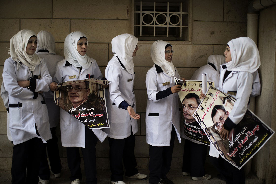 Palestinian nurses hold posters of Maisara Abu Hamdiyeh, a Palestinian prisoner who died of cancer while in Israeli detention, outside Al-Ahli hospital in the West Bank city of Hebron ahead of his funeral on April 4, 2013. The Palestinian leadership has accused Israel of medical negligence, despite moves by the prison service to secure his early release on compassionate grounds, with news of his death sparking angry clashes with the army, notably in Hebron.