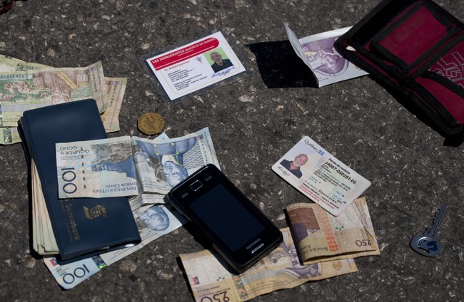 Identification cards, cash, a phone, a key and an item with a bank logo lay on the street after being placed there by authorities next to the body of Canadian priest Richard E. Joyal, not in picture, after he was killed in Delmas, a district of Port-au-Prince, Haiti, Thursday, April 25, 2013. Police inspector Aladin Jean-Louis says that the 62-year-old Joyal had just withdrawn $1,000 from a bank when two men on a motorcycle approached and grabbed a bag he was carrying, and the passenger shot him three times in the back. Authorities later found the $1,000 in Joyal’s wallet in his pocket and placed it at his feet. (AP Photo/Dieu Nalio Chery).