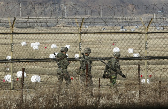 South Korean army soldiers patrol along a barbed-wire fence near the border village of Panmunjom in Paju, South Korea, Monday, April 8, 2013.