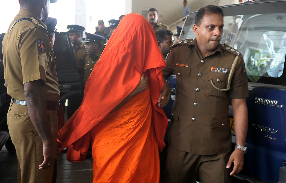 A Sri Lankan police officer escorts an arrested Buddhist monk to a magistrates’ court in the suburb of Gangodavila in Colombo on April 2, 2013, in connection with a mob attack against a Muslim-owned clothing store near the capital on March 28. A total of three monks and 14 other suspects were released after police and the victim agreed to drop charges in a case that had raise religious tensions in the country.