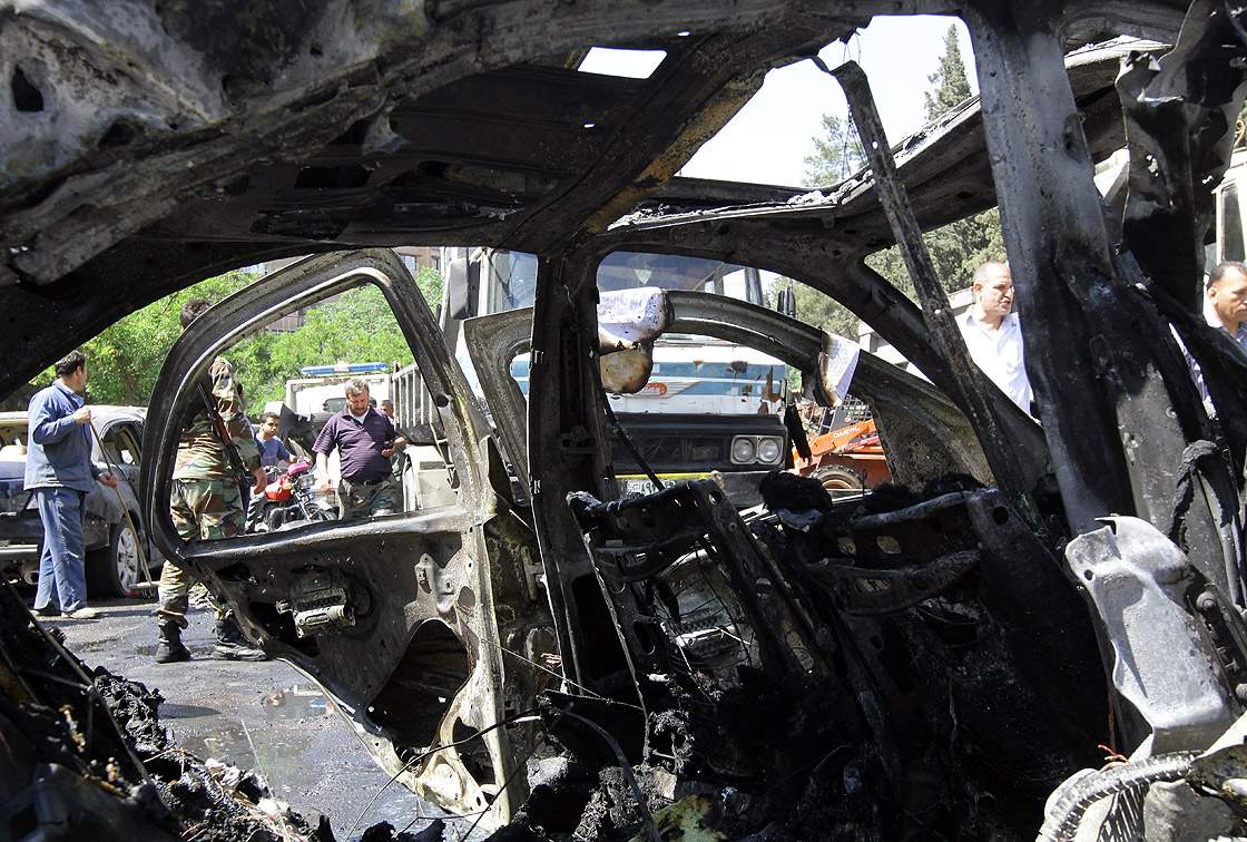 A Syrian officer is seen through the wreckage of a vehicle following an explosion in the Mazzeh district of the Syrian capital Damascus on April 29, 2013, which is believed to have targeted the prime minister's convoy.