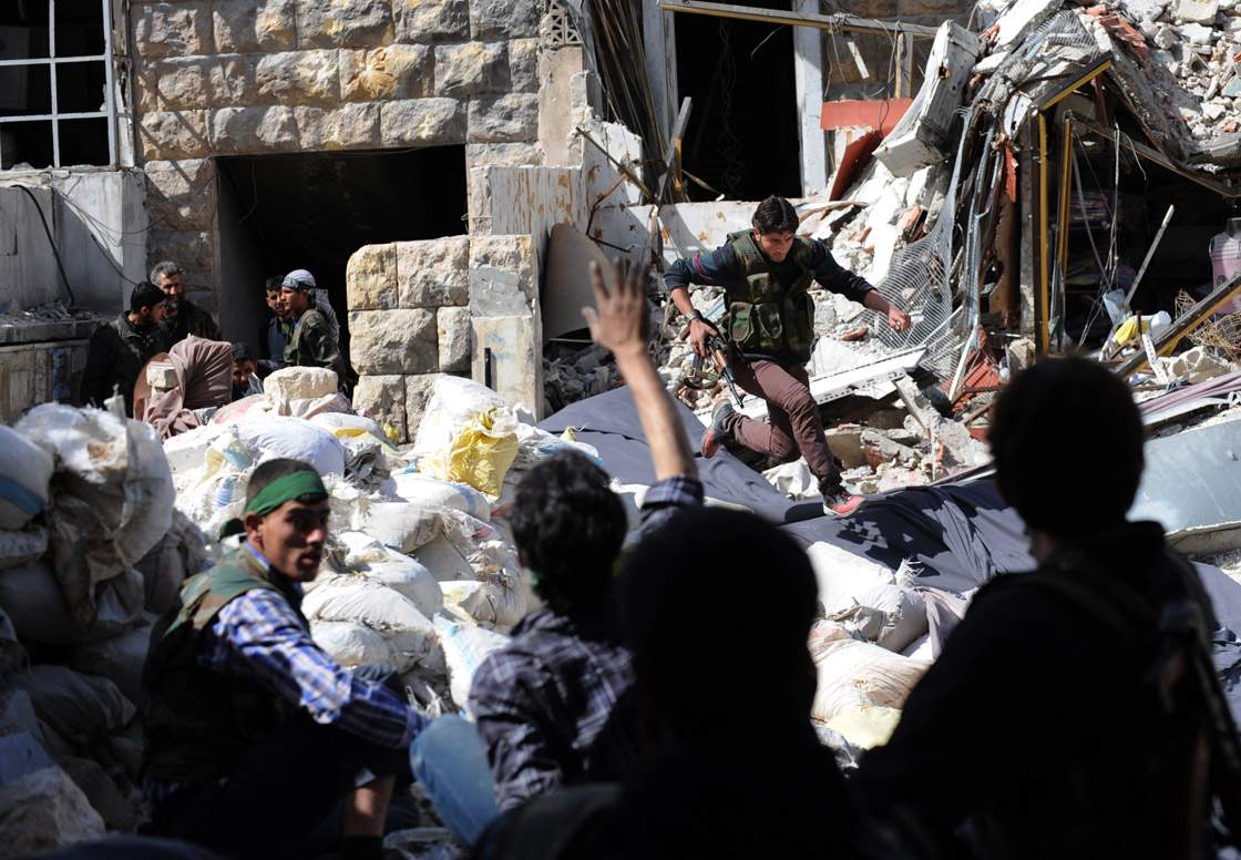 A Syrian opposition fighter runs for cover from Syrian army snipers as they try to cross the rubble during clashes in the northern city of Aleppo on March 27, 2013. 
