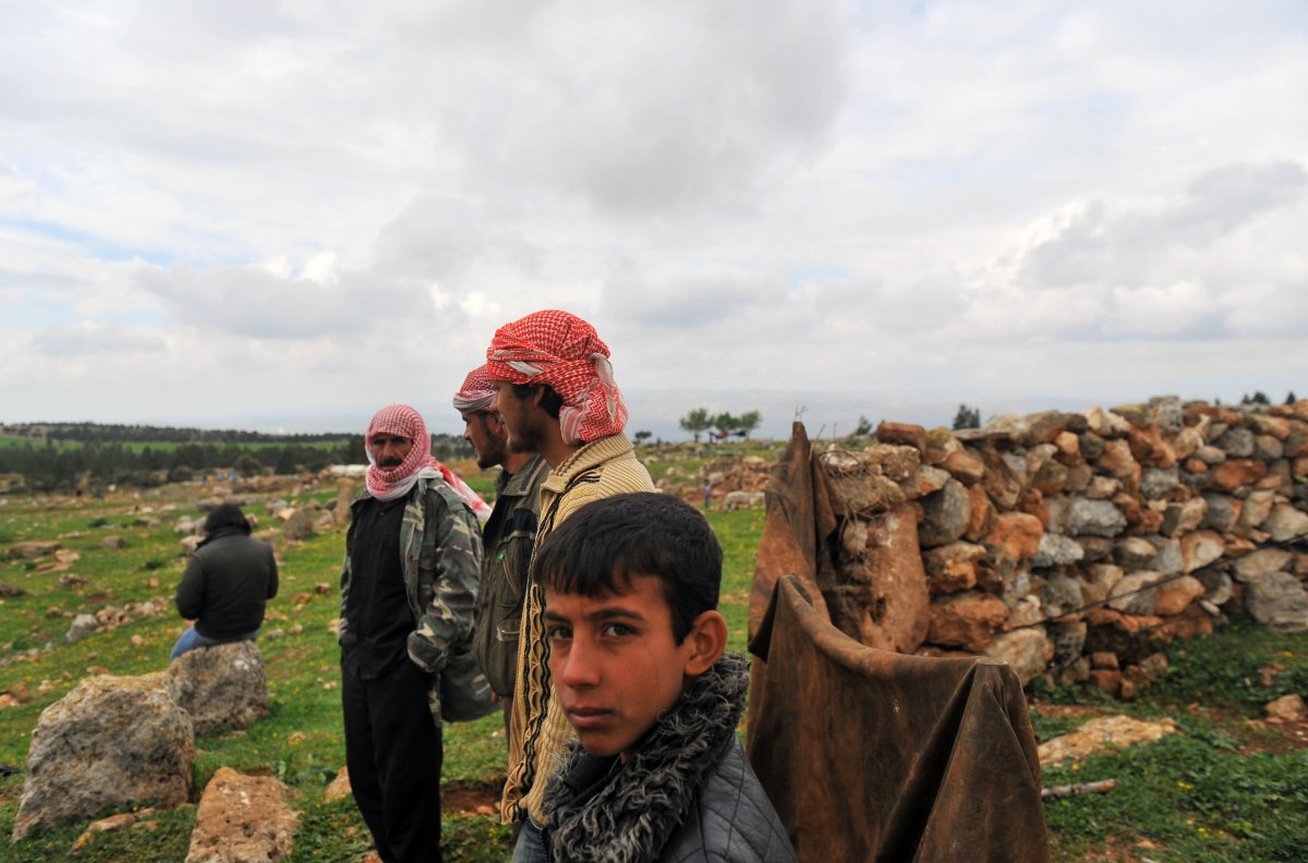 Syrians gather in a field near their makeshift refugee camp in the mountains in the area of Kherbet al-Khaldiye, on the Syria-Turkey border, on March 28, 2013. Refugees living in this area are living off herbs and stagnant rain water they are collecting for drinking and washing.