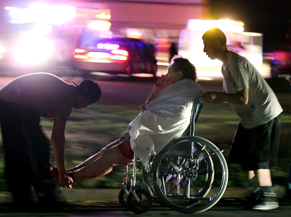 An injured elderly person is assisted by two young males as a nursing home is evacuated on April 17, 2013. (AP Photo)