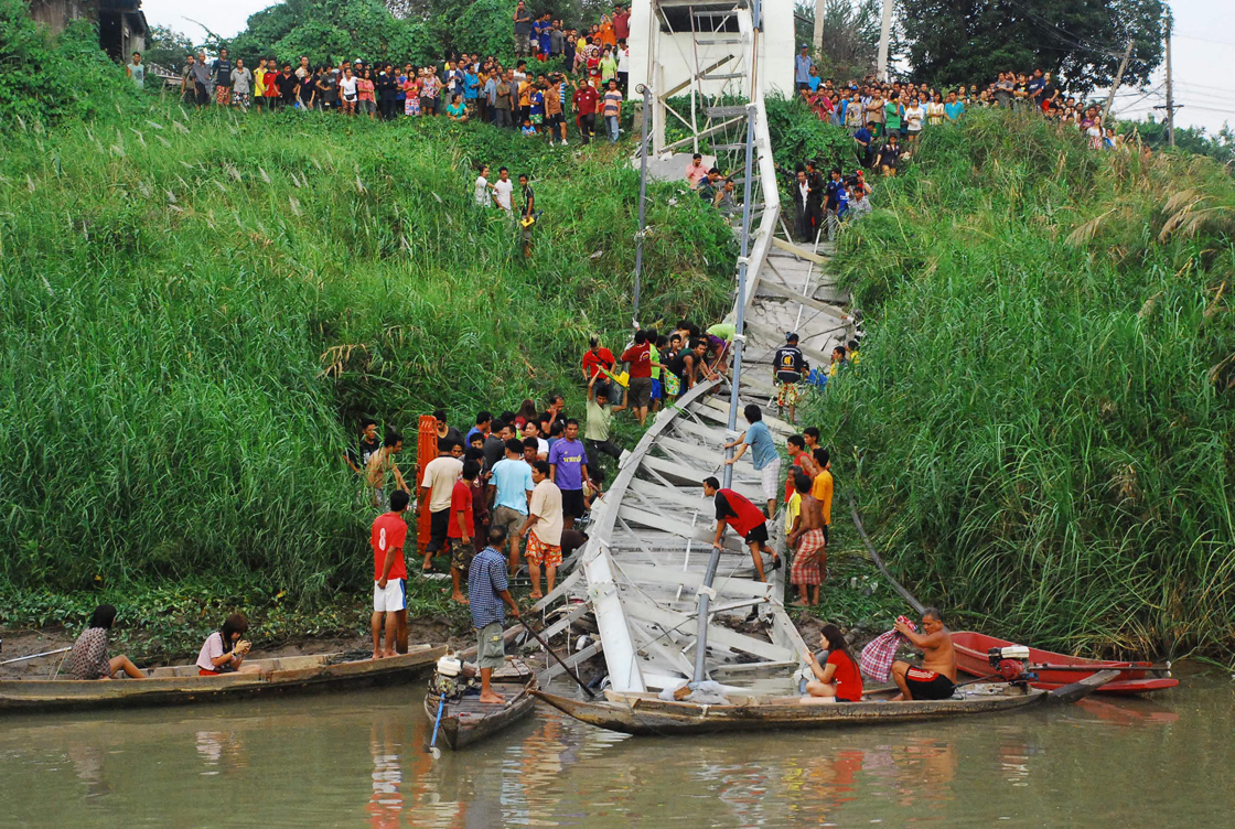 Thai villagers and rescuers look for survivors under the wreckage of a suspension bridge crossing the Pasak river after it collapsed Sunday, April 28, 2013 in Ayutthaya province, central Thailand. Police say at least four people have been killed and a dozen have been injured when the small bridge collapsed in the accident. 