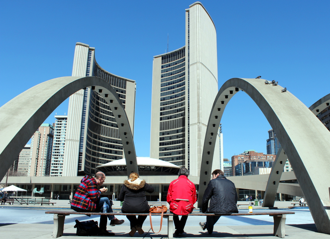 People sit outside of Toronto City Hall.