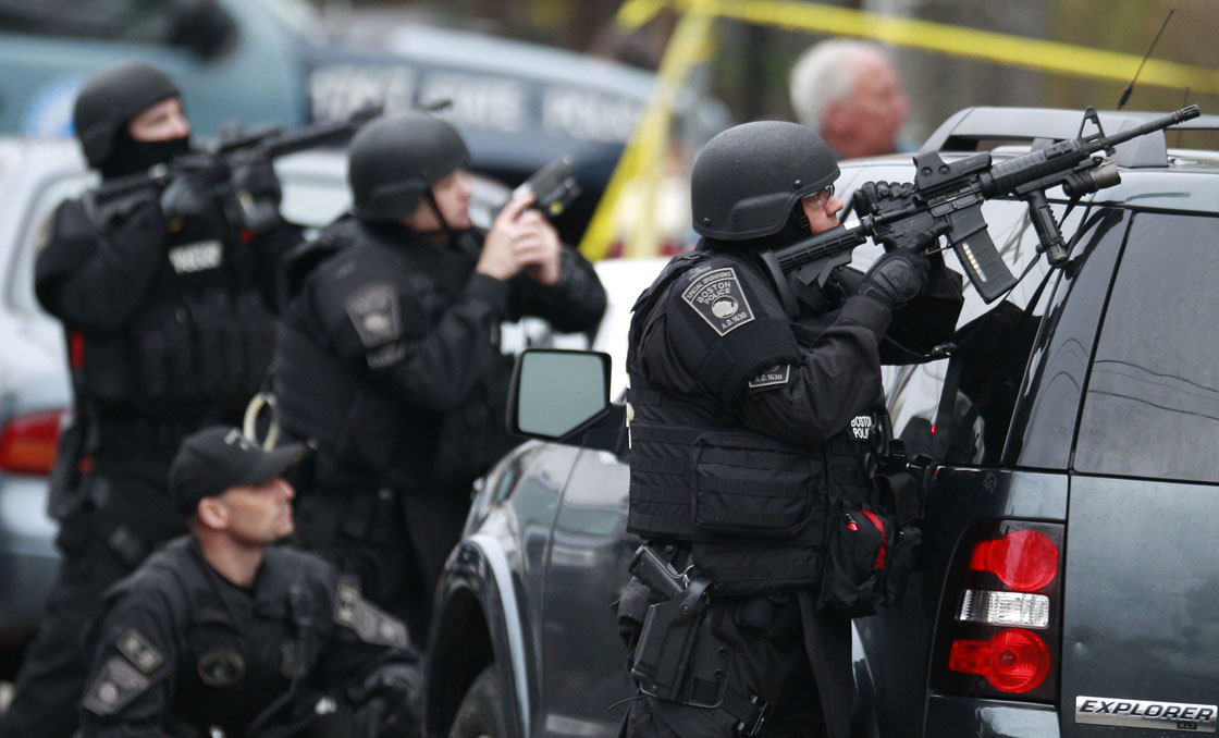 Police in tactical gear surround an apartment building while looking for a suspect in the Boston Marathon bombings in Watertown, Mass., Friday, April 19, 2013. 
