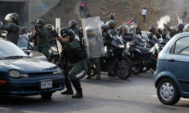Riot police fire rubber bullets as demonstrators throw rocks against them during clashes after opposition supporters and students blocked a highway in the Altamira neighborhood in Caracas, Venezuela, Monday, April 15, 2013. (AP Photo/Fernando Llano) .