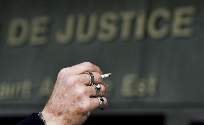 A man smokes a cigarette outside the Montreal courthouse, Monday, March 12, 2012 on the opening day of a massive lawsuit against the tobacco industry. 