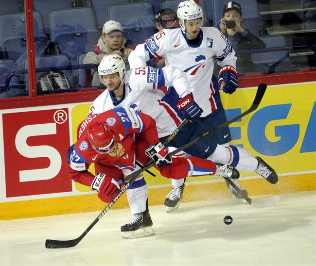 French players Jonathan Janil (55) and Tim Bozon (15) take down Russia's Alexei Tereshenko during the 2013 Ice Hockey IIHF World Championships.