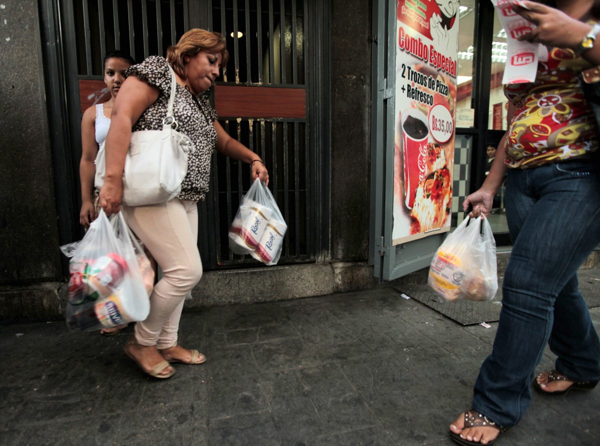 A customer leaves a private super market with her purchases, including toilet paper, in Caracas, Venezuela, Wednesday, May 15, 2013. First milk, butter, coffee and cornmeal ran short. Now Venezuela is running out of the most basic of necessities - toilet paper.