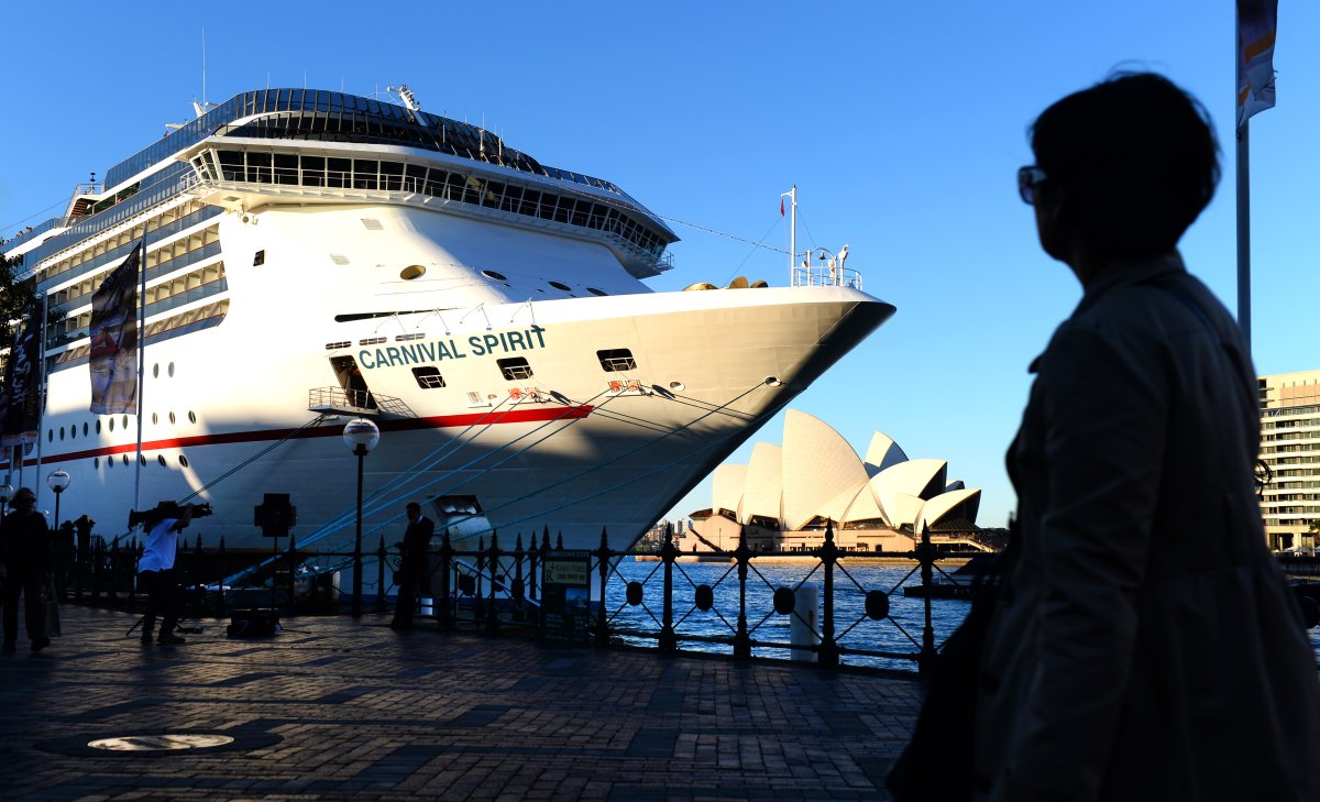 A woman walks past  the cuise ship Carnival Spirit at Sydney's Circular Quay, on May 9, 2013.  A search was underway off Australia for a couple fell overboard into shark-infested waters from the cruise ship returning to Sydney from a Pacific tour.  The Carnival Spirit liner docked at Circular Quay in Sydney Thursday morning and the 30-year-old man and 27-year-old woman were reported missing. 