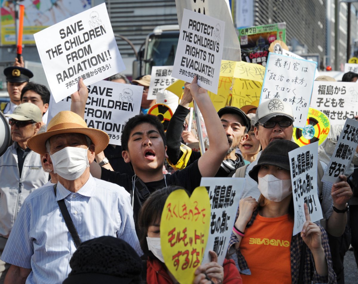 Protesters carry placards as they march in Tokyo's shopping district of Shinjuku on May 18, 2013 calling for the evacuation of children still living in the Fukushima prefecture area. Two years since the worst nuclear accident in a generation erupted, the nuclear plant in Fukushima remains fragile and fears and uncertainties still remain for people living in the region.  